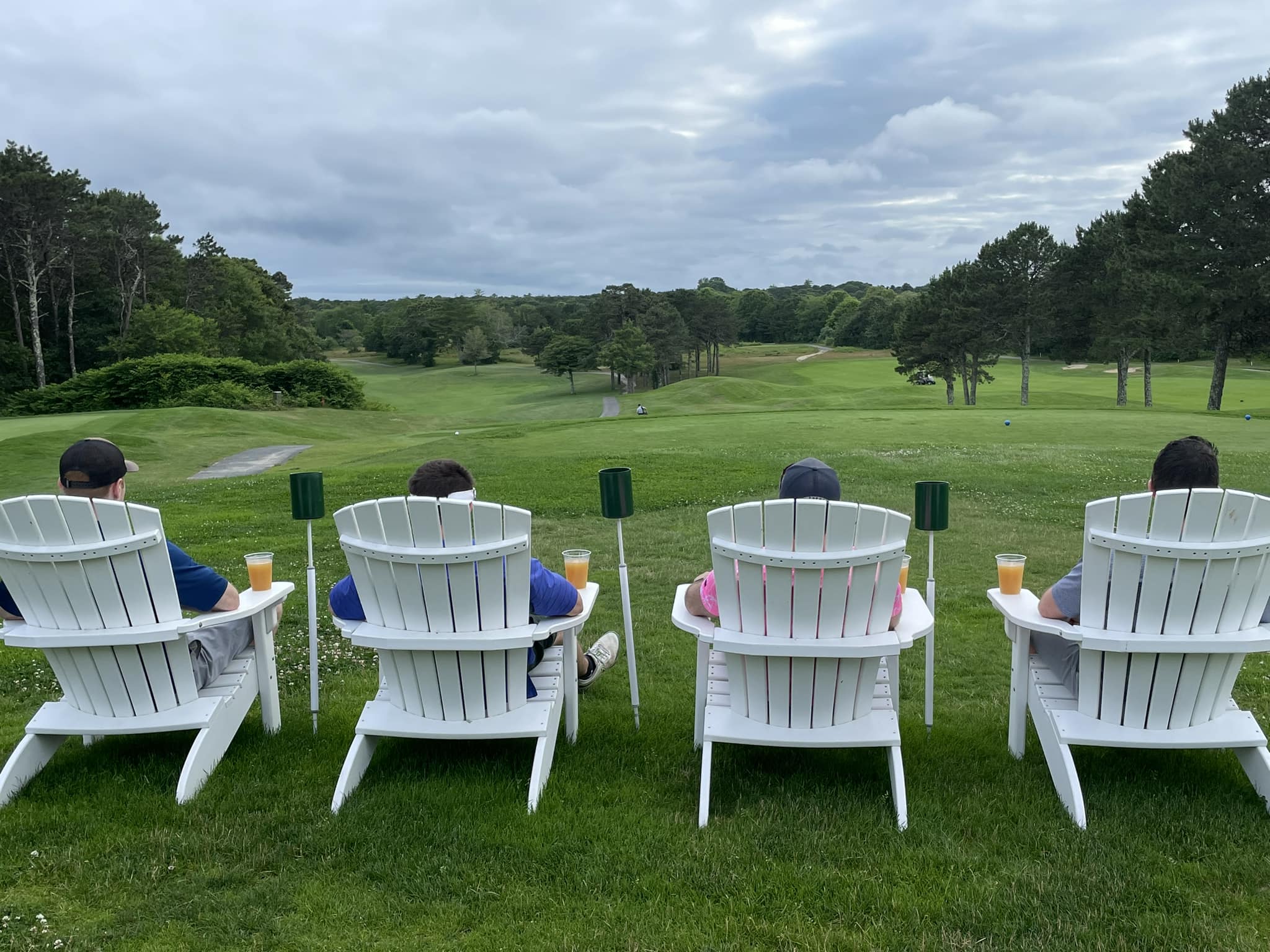Guests relaxing in Adirondack chairs overlooking the green